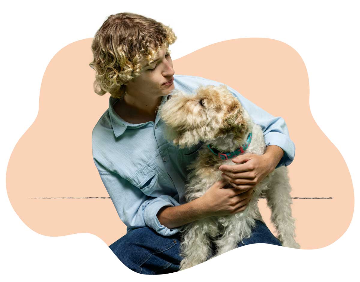 A man in a light blue shirt holding his Schnauzer in his lap