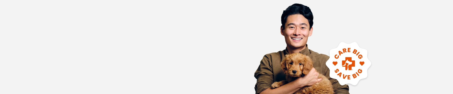 A man in a brown shirt smiling holding a small brown-haired dog